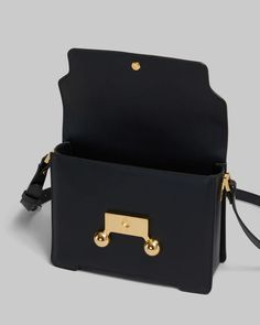 FINAL SALE The Black Leather Trunkaroo Medium Shoulder Bag by Marni is a rectangular shoulder bag featuring a front flap with magnetic closure and engraved Marni lettering, contoured base, and oversized stud detail. Detachable and adjustable buckled shoulder strap: can also be worn as a clutch. Made in Italy Body: 100% Calf Leather - Lining: 100% Ovine Leather - Metallic Parts: 100% Brass - Metallic Parts: 100% Steel SBMP0195U0P694800N99 Modern Rectangular Flap Bag With Branded Hardware, Designer Rectangular Flap Bag With Metal Hardware, Rectangular Flap Bag With Metal Hardware For Work, Rectangular Workwear Flap Bag With Metal Hardware, Rectangular Saddle Bag With Magnetic Closure, Modern Rectangular Saddle Bag With Branded Hardware, Designer Rectangular Saddle Bag For Work, Boot Pumps, Medium Bags