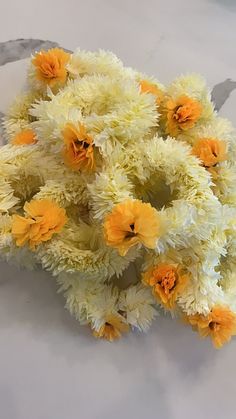 a bunch of white and yellow flowers sitting on top of a marble countertop next to a knife