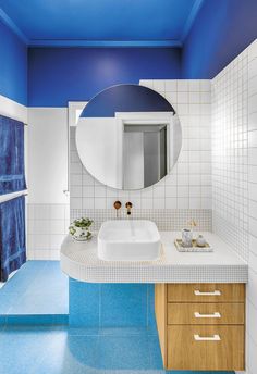 a bathroom with blue and white walls, tile flooring and a round mirror on the wall