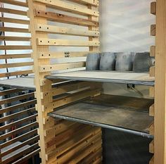 the shelves are made out of pallets and have metal trays on each shelf