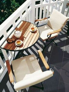 two chairs sitting on top of a wooden deck next to a table with cups of coffee