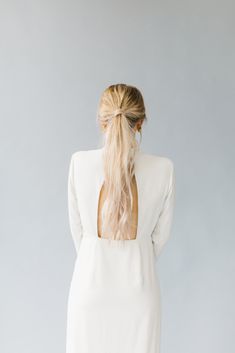 the back of a woman's head with long blonde hair wearing a white dress