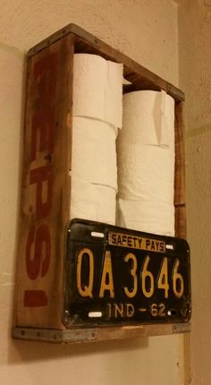 an old wooden box with two rolls of toilet paper on it hanging from the wall