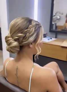 a woman sitting in front of a mirror with her back turned to the camera, wearing a bra