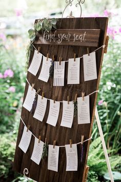 a wooden sign with notes hanging from it's sides in front of some flowers