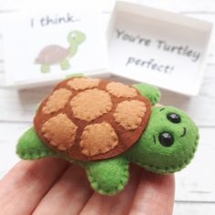 a hand holding a small stuffed animal turtle