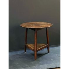 a small wooden table sitting on top of a cement floor next to a gray wall