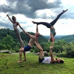 three people doing handstands on top of a hill with trees in the background