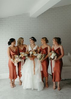 a group of women standing next to each other holding bouquets in their hands and laughing