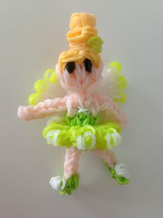 a small plastic doll with yellow hair and green pants on it's legs, holding a string