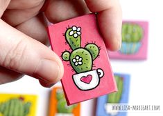 a hand holding a small card with a cactus on it and hearts in the middle