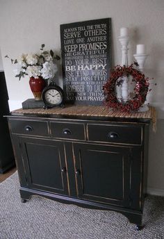 there is a black cabinet with two clocks on top and flowers in vases next to it