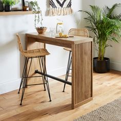 a wooden table with two chairs next to it and a potted plant in the corner