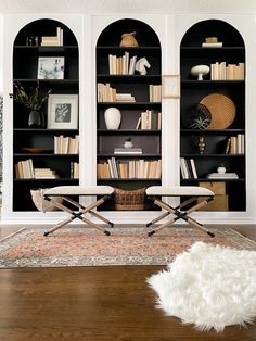 a living room filled with furniture and bookshelves next to a rug on top of a hard wood floor