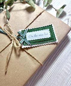 a gift wrapped in brown paper with a green ribbon and tag that says on the nice list