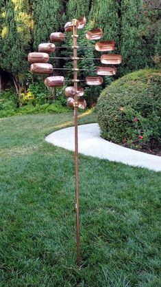 a tall metal sculpture with donuts on it's sides in the grass next to a path