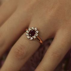 a woman's hand with a diamond and ruby ring on top of her finger