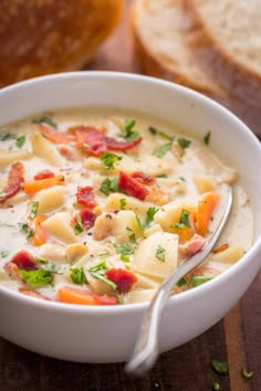 a close up of a bowl of soup on a wooden table with bread in the background