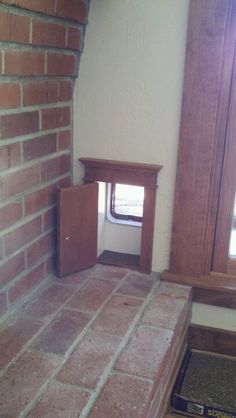 the corner of a room with a small window and brick flooring in front of it