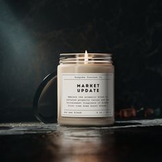 a candle sitting on top of a wooden table next to a black mug with the words market update written on it