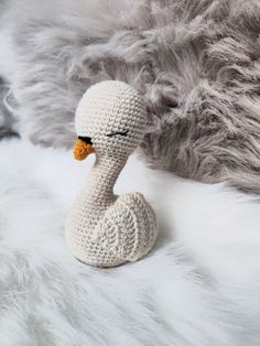 a crocheted duck sitting on top of a white fur covered floor