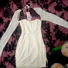 a white dress is laying on a pink and black floral print bed spread with an empty tag attached to it