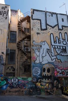 graffiti on the side of an old building with spiral staircase and fire escape in the background