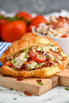 a close up of a sandwich on a cutting board with other food in the background