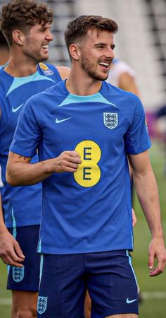 two men in blue soccer uniforms standing next to each other