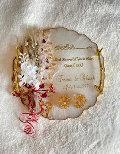 a plate with some flowers on it sitting on a bed next to a couple's wedding rings