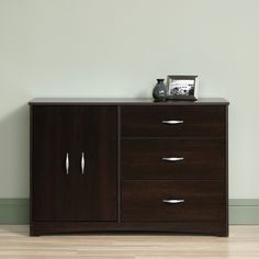 a wooden cabinet with three drawers and a silver vase on top