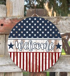 an american flag welcome sign hanging on a wooden fence