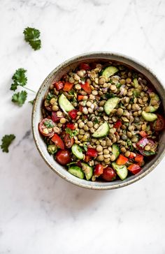 a bowl filled with vegetables on top of a white counter next to some parsley