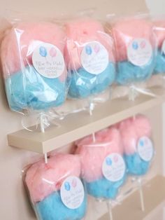 some pink and blue cupcakes are in plastic bags on a shelf with tags