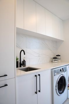 a washer and dryer in a white kitchen with marble backsplashing