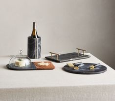 a table topped with two trays filled with cheese and wine next to a bottle