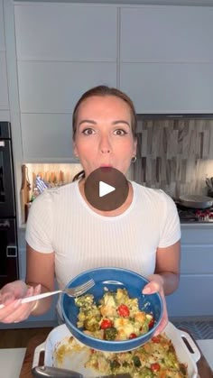 a woman is holding a bowl of food in her hands and making a funny face