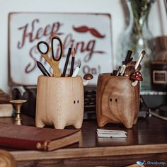 two wooden pencil holders sitting on top of a desk