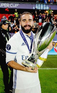 a man holding a soccer trophy in front of a crowd on a field at a sporting event