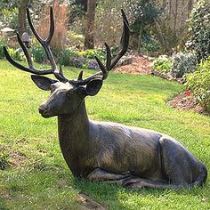 a statue of a deer laying in the grass