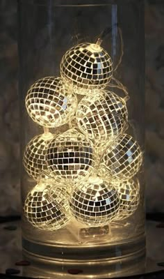 a glass container filled with disco balls on top of a table