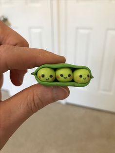 two peas in a pea pod with faces drawn on them, being held by someone's hand