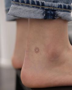 a small sun tattoo on the ankle