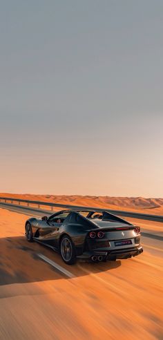 two black sports cars driving on the highway in the desert at sunset or sunrise time