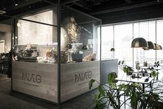 a restaurant with glass walls and plants in the center, along with menus on the wall