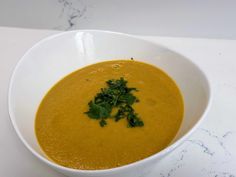 a white bowl filled with soup and garnished with cilantro on top