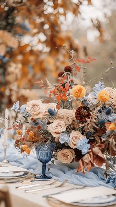 an arrangement of flowers on a table with place settings