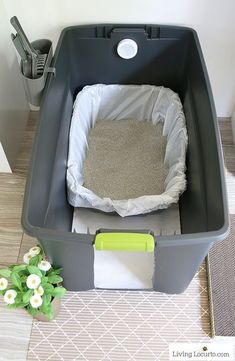 a large grey trash can sitting on top of a floor next to a flower pot