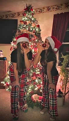 two young women standing in front of a christmas tree