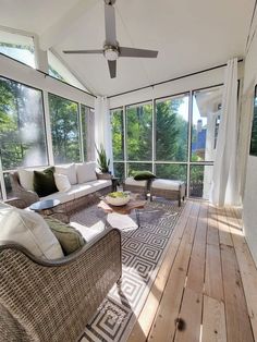 a sun room with wicker furniture and large windows overlooking the trees in the background